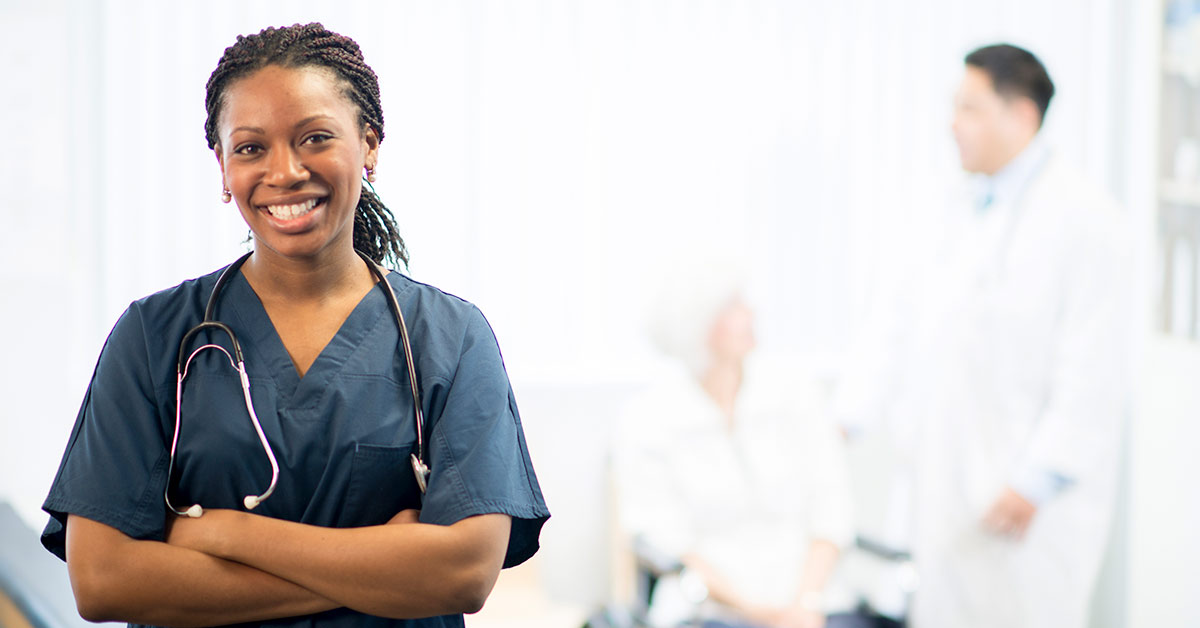 a nurse facing the camera while a doctor speaks to the patient in the background